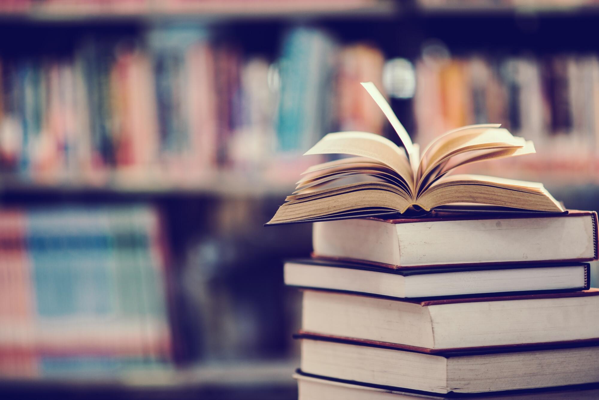 Des livres sont empilés avec un livre ouvert sur le dessus